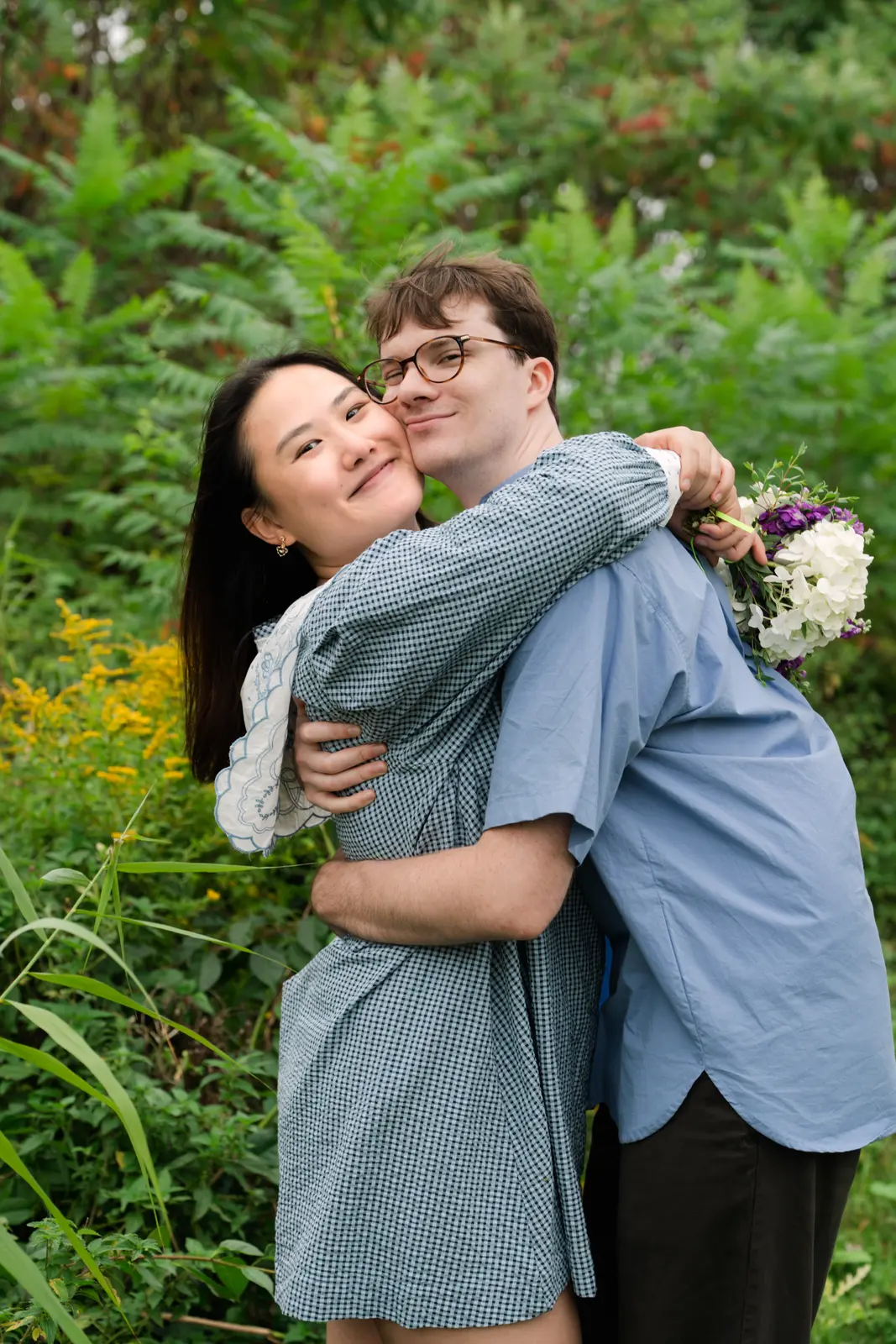 Angela and Sean embracing among the garden ferns