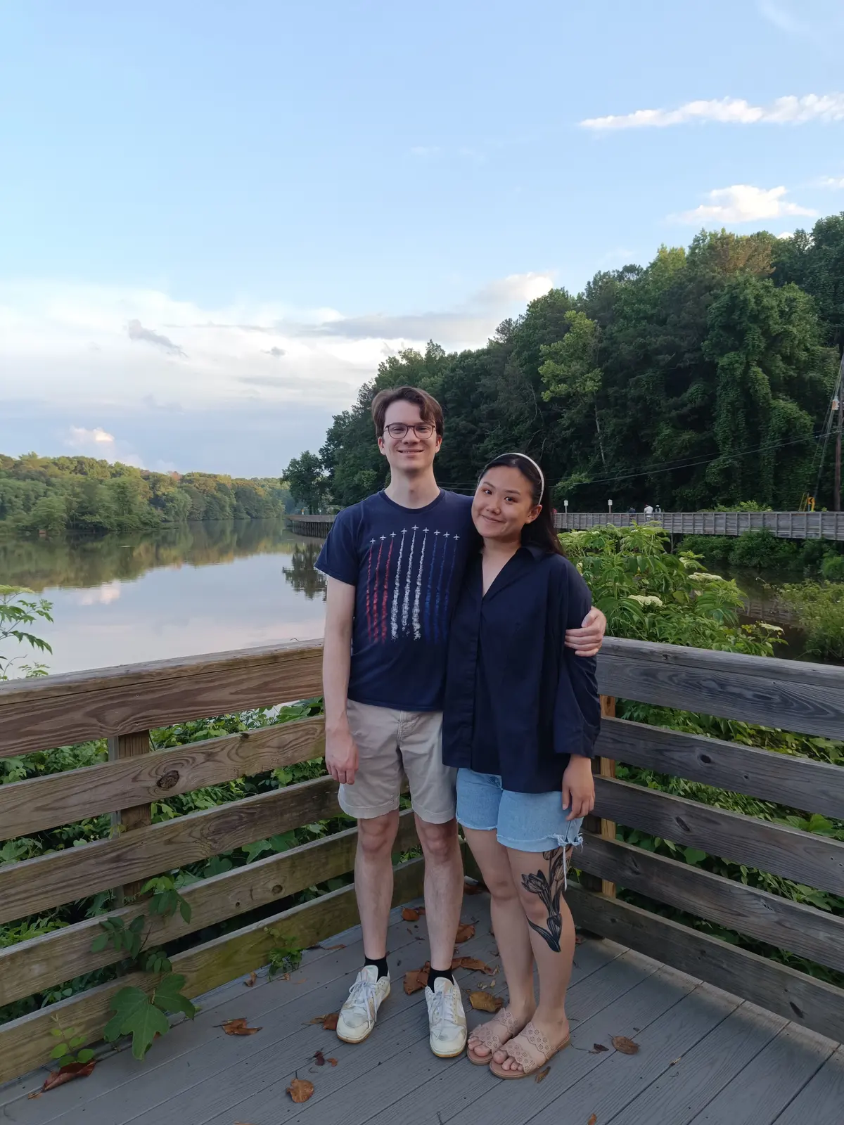 Angela and Sean arm in arm on a riverside boardwalk